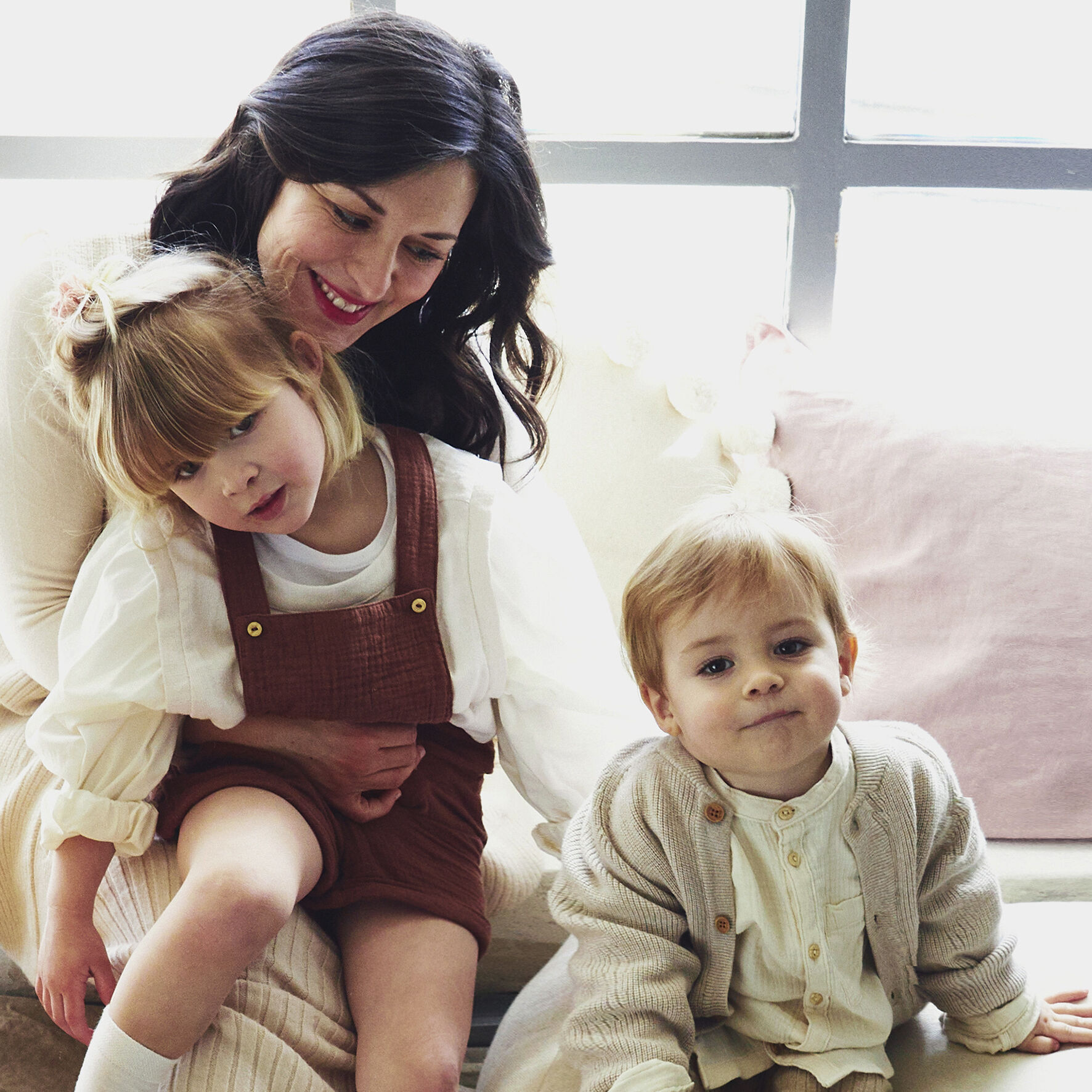 Eine Mutter mit zwei Kindern auf einem Sofa.