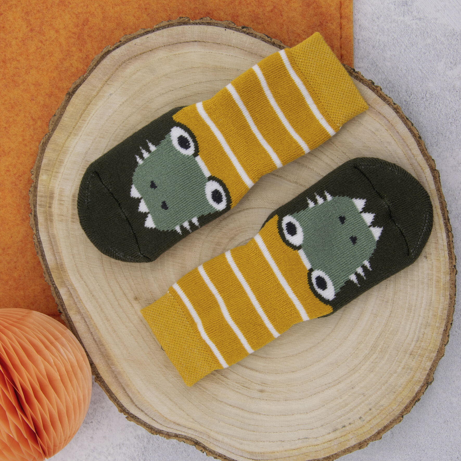 Krokodilstoppersocken, gelegt auf einer Holzscheibe.
