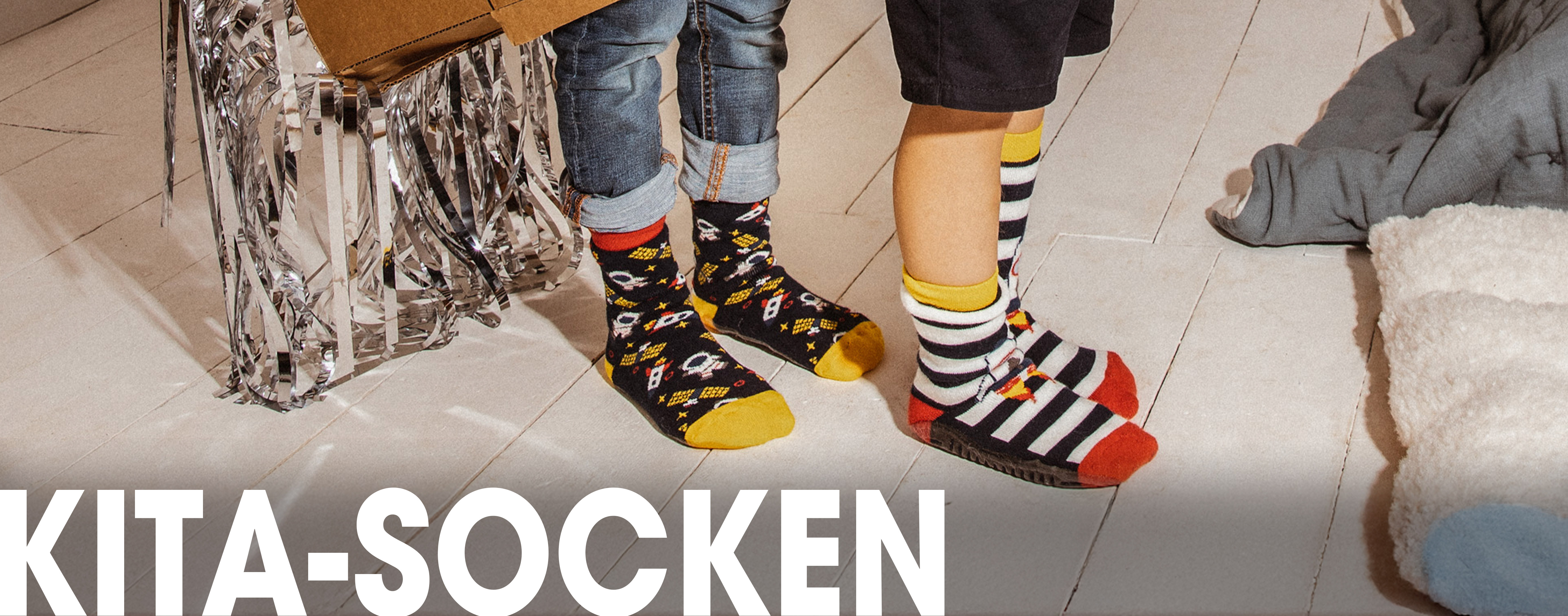 Zwei Kinder, die Stoppersocken mit Weltallmotiven tragen.