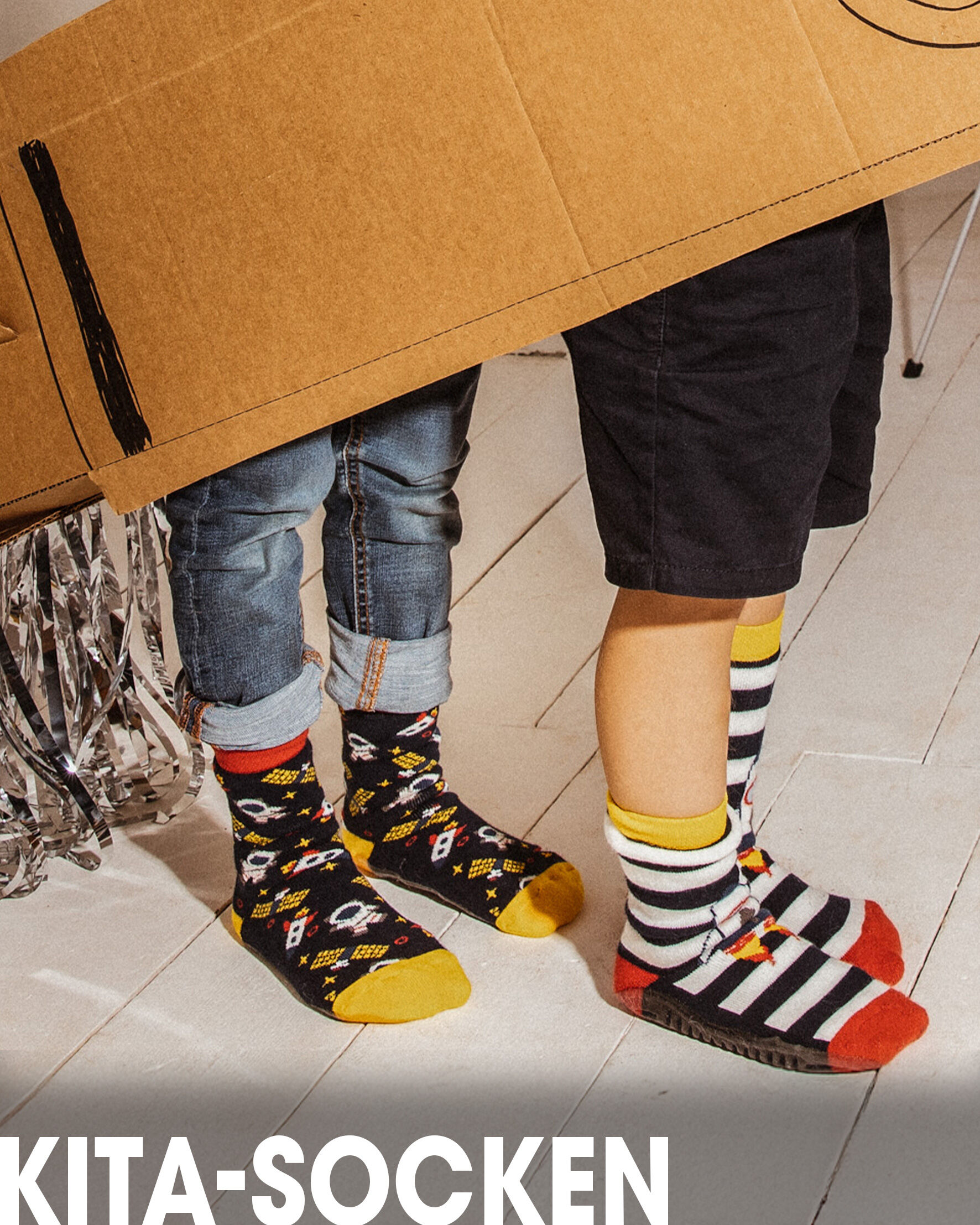 Zwei Kinder, die Stoppersocken mit Weltallmotiven tragen.